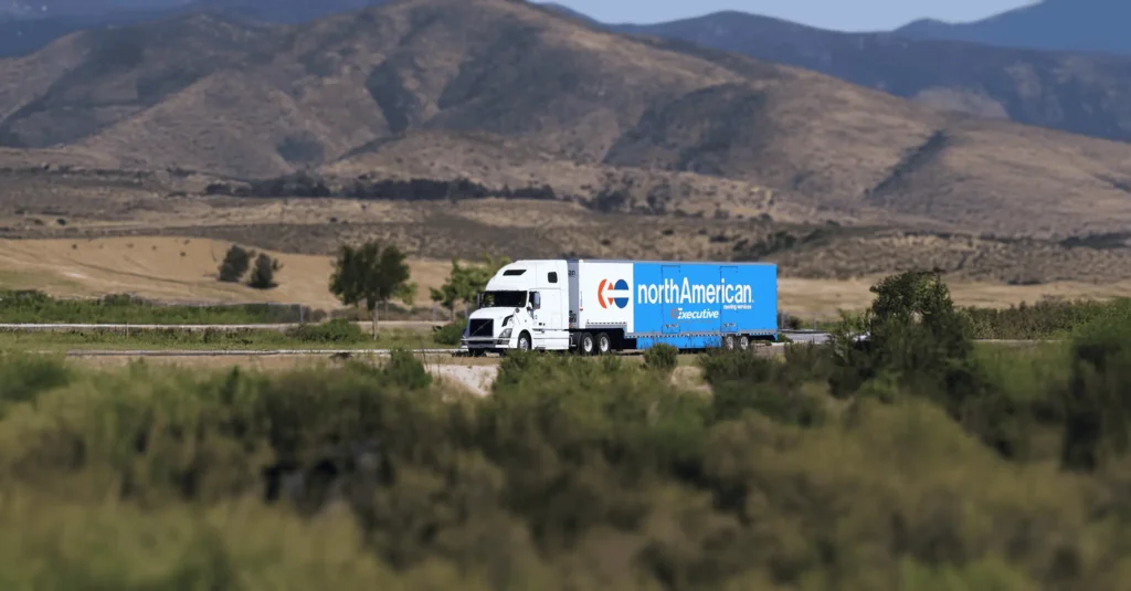 NorthAmerican Van Lines truck on freeway with mountains in background.